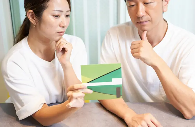 住宅模型を前に困った表情で相談する夫婦