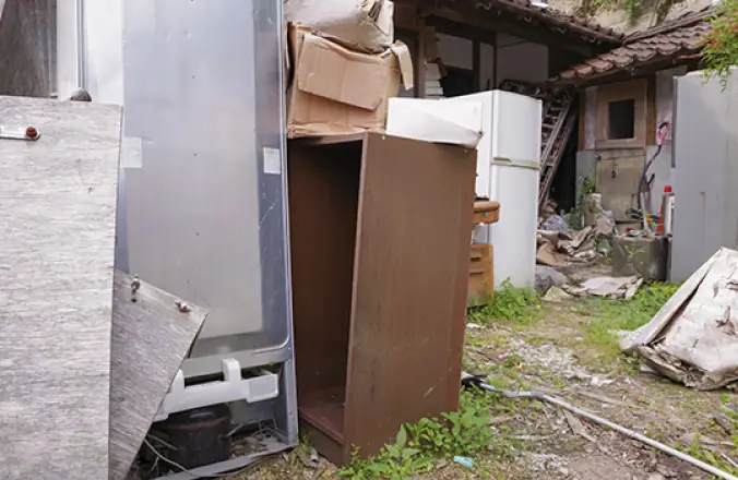 不用品やごみが不法投棄された空き家の裏手
